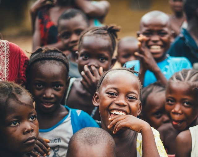 Children and young people seated together in a community hall during a local gathering in Plateau State.
